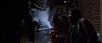 Movie still from “American Psycho” (2000), directed by Mary Harron – A man and a dog in a dark alleyway; Medium shot, High angle