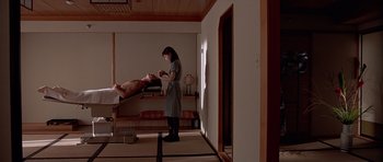 Movie still from “American Psycho” (2000), directed by Mary Harron – A woman standing next to a man in a room; Medium shot, Low angle