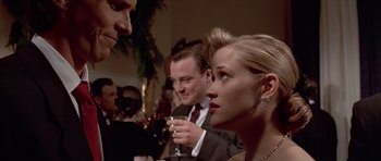Movie still from “American Psycho” (2000), directed by Mary Harron – A group of people sitting at a table with drinks; Close Up shot, Over the shoulder angle