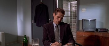 Movie still from “American Psycho” (2000), directed by Mary Harron – A man in a suit and tie writing on a piece of paper; Medium shot, High angle