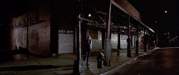 Movie still from “American Psycho” (2000), directed by Mary Harron – A woman standing next to a fire hydrant in an empty warehouse; Wide shot, High angle