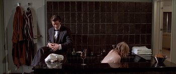 Movie still from “American Psycho” (2000), directed by Mary Harron – A man and a woman are sitting at a bar; Medium shot, Over the shoulder angle