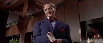 Movie still from “American Psycho” (2000), directed by Mary Harron – A man in a suit and bow tie holding a shoe; Close Up shot, Low angle