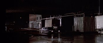 Movie still from “American Psycho” (2000), directed by Mary Harron – A car is parked on the side of the road at night; Extreme Wide shot, High angle