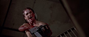 Movie still from “American Psycho” (2000), directed by Mary Harron – A man with blood all over his face holding a machine; Medium shot, Low angle