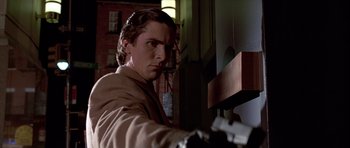 Movie still from “American Psycho” (2000), directed by Mary Harron – A man holding a gun in a room; Close Up shot, Low angle