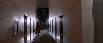 Movie still from “American Psycho” (2000), directed by Mary Harron – A woman running down a long hallway in a building; Extreme Wide shot, High angle