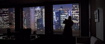 Movie still from “American Psycho” (2000), directed by Mary Harron – A man taking a picture of a large city at night; Extreme Wide shot, Low angle