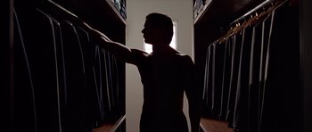 Movie still from “American Psycho” (2000), directed by Mary Harron – A man is standing in a closet in the dark; Medium shot, Low angle