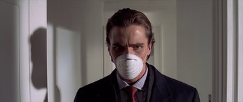 Movie still from “American Psycho” (2000), directed by Mary Harron – A man wearing a face mask while standing in front of a door; Close Up shot, Low angle