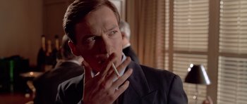 Movie still from “American Psycho” (2000), directed by Mary Harron – A man smoking a cigarette while wearing a suit and tie; Close Up shot, Low angle