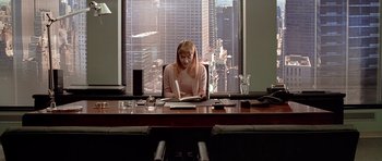 Movie still from “American Psycho” (2000), directed by Mary Harron – A woman sitting at a desk in front of a laptop computer; Medium shot, Low angle