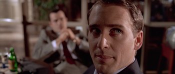 Movie still from “American Psycho” (2000), directed by Mary Harron – A man's face in front of another man in a suit; Close Up shot, Over the shoulder angle