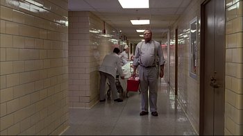 Movie still from “American Splendor” (2003), directed by Shari Springer Berman – A man standing in the hallway of a building; Wide shot, Low angle