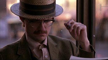 Movie still from “American Splendor” (2003), directed by Shari Springer Berman – A man in a straw hat and glasses holding a cigarette; Close Up shot, Low angle