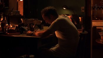 Movie still from “American Splendor” (2003), directed by Shari Springer Berman – A man sitting at a table writing on a piece of paper; Medium shot, Low angle