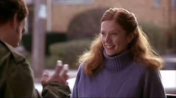 Movie still from “American Splendor” (2003), directed by Shari Springer Berman – A woman in a purple sweater smiling for the camera; Medium shot, Over the shoulder angle