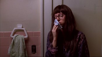 Movie still from “American Splendor” (2003), directed by Shari Springer Berman – A woman sitting in front of a bathroom mirror holding a tissue to her nose; Close Up shot, High angle