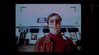 Movie still from “American Splendor” (2003), directed by Shari Springer Berman – A man wearing a brown jacket and a red shirt; Medium shot, Low angle