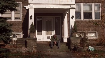 Movie still from “American Splendor” (2003), directed by Shari Springer Berman – A man sitting on the front steps of a house; Wide shot, Low angle