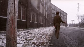 Movie still from “American Splendor” (2003), directed by Shari Springer Berman – A man walking down a street in the snow; Wide shot, Over the shoulder angle