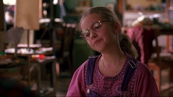 Movie still from “American Splendor” (2003), directed by Shari Springer Berman – A young girl wearing glasses sitting in front of a table; Close Up shot, Over the shoulder angle