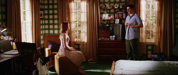 Movie still from “American Wedding” (2003), directed by Jesse Dylan – A woman sitting on top of an ottoman next to a bed; Wide shot, High angle