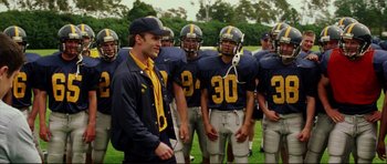 Movie still from “American Wedding” (2003), directed by Jesse Dylan – A group of football players standing next to each other on a field; Medium shot, Over the shoulder angle