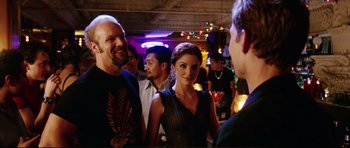 Movie still from “American Wedding” (2003), directed by Jesse Dylan – A group of people standing in a room with lights in the background; Medium shot, Over the shoulder angle