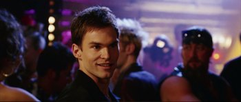 Movie still from “American Wedding” (2003), directed by Jesse Dylan – A young man smiling for the camera in a nightclub; Close Up shot, Over the shoulder angle