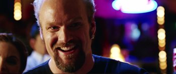Movie still from “American Wedding” (2003), directed by Jesse Dylan – A person with a beard smiling; Close Up shot, Over the shoulder angle