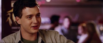 Movie still from “American Wedding” (2003), directed by Jesse Dylan – A young man is smiling for the camera; Close Up shot, Over the shoulder angle