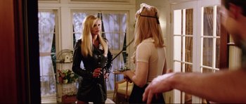 Movie still from “American Wedding” (2003), directed by Jesse Dylan – Two women in a room one is holding a whip and the other is holding a cane; Medium shot, Over the shoulder angle