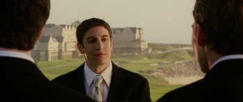 Movie still from “American Wedding” (2003), directed by Jesse Dylan – A man in a suit and tie standing in front of a golf course; Close Up shot, Over the shoulder angle