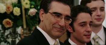 Movie still from “American Wedding” (2003), directed by Jesse Dylan – A person wearing a suit and glasses; Close Up shot, Over the shoulder angle