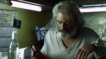 Movie still from “Amores Perros” (2000), directed by Alejandro G. Iñárritu – An old man with a beard is looking down at something; Close Up shot, Low angle