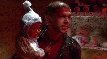 Movie still from “Amores Perros” (2000), directed by Alejandro G. Iñárritu – A man holding a baby in his arms and wearing a hat; Close Up shot, Low angle