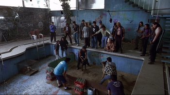 Movie still from “Amores Perros” (2000), directed by Alejandro G. Iñárritu – A group of people standing in a room with crates; Wide shot, High angle