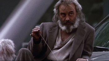 Movie still from “Amores Perros” (2000), directed by Alejandro G. Iñárritu – An older man with long grey hair holding a string; Medium shot, Low angle