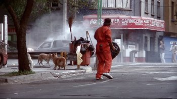 Movie still from “Amores Perros” (2000), directed by Alejandro G. Iñárritu – A man in orange is walking down the street with two dogs; Wide shot, High angle
