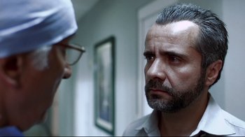 Movie still from “Amores Perros” (2000), directed by Alejandro G. Iñárritu – A man with a gray beard and glasses looking at another man with a gray beard and eyeglasses; Close Up shot, Over the shoulder angle