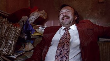 Movie still from “Amores Perros” (2000), directed by Alejandro G. Iñárritu – A man in a suit and tie sitting in a pile of papers; Medium shot, Overhead angle