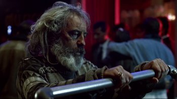 Movie still from “Amores Perros” (2000), directed by Alejandro G. Iñárritu – A man with a long beard sitting next to a railing; Close Up shot, Low angle