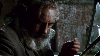 Movie still from “Amores Perros” (2000), directed by Alejandro G. Iñárritu – An old man with a beard is looking down at a cigarette; Close Up shot, Low angle