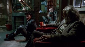 Movie still from “Amores Perros” (2000), directed by Alejandro G. Iñárritu – Two men sitting on a red chair in a room; Wide shot, Low angle