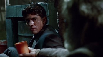 Movie still from “Amores Perros” (2000), directed by Alejandro G. Iñárritu – A person sitting in a chair holding a cup; Close Up shot, Over the shoulder angle