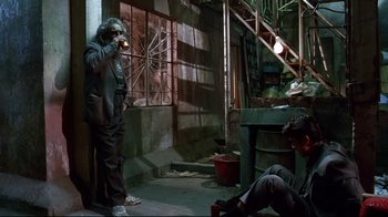 Movie still from “Amores Perros” (2000), directed by Alejandro G. Iñárritu – A man holding an umbrella while standing next to another man; Wide shot, High angle
