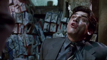 Movie still from “Amores Perros” (2000), directed by Alejandro G. Iñárritu – A man wearing a suit and tie in front of a pile of papers; Close Up shot, Low angle