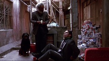 Movie still from “Amores Perros” (2000), directed by Alejandro G. Iñárritu – A man sitting on the ground next to another man; Wide shot, Low angle