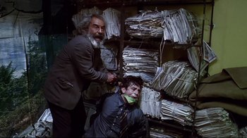 Movie still from “Amores Perros” (2000), directed by Alejandro G. Iñárritu – Two men in a room with stacks of papers; Medium shot, Low angle